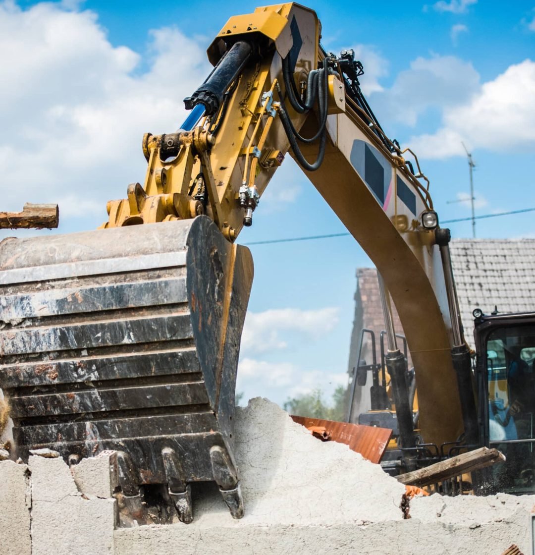 Mechanical digger demolishing building.